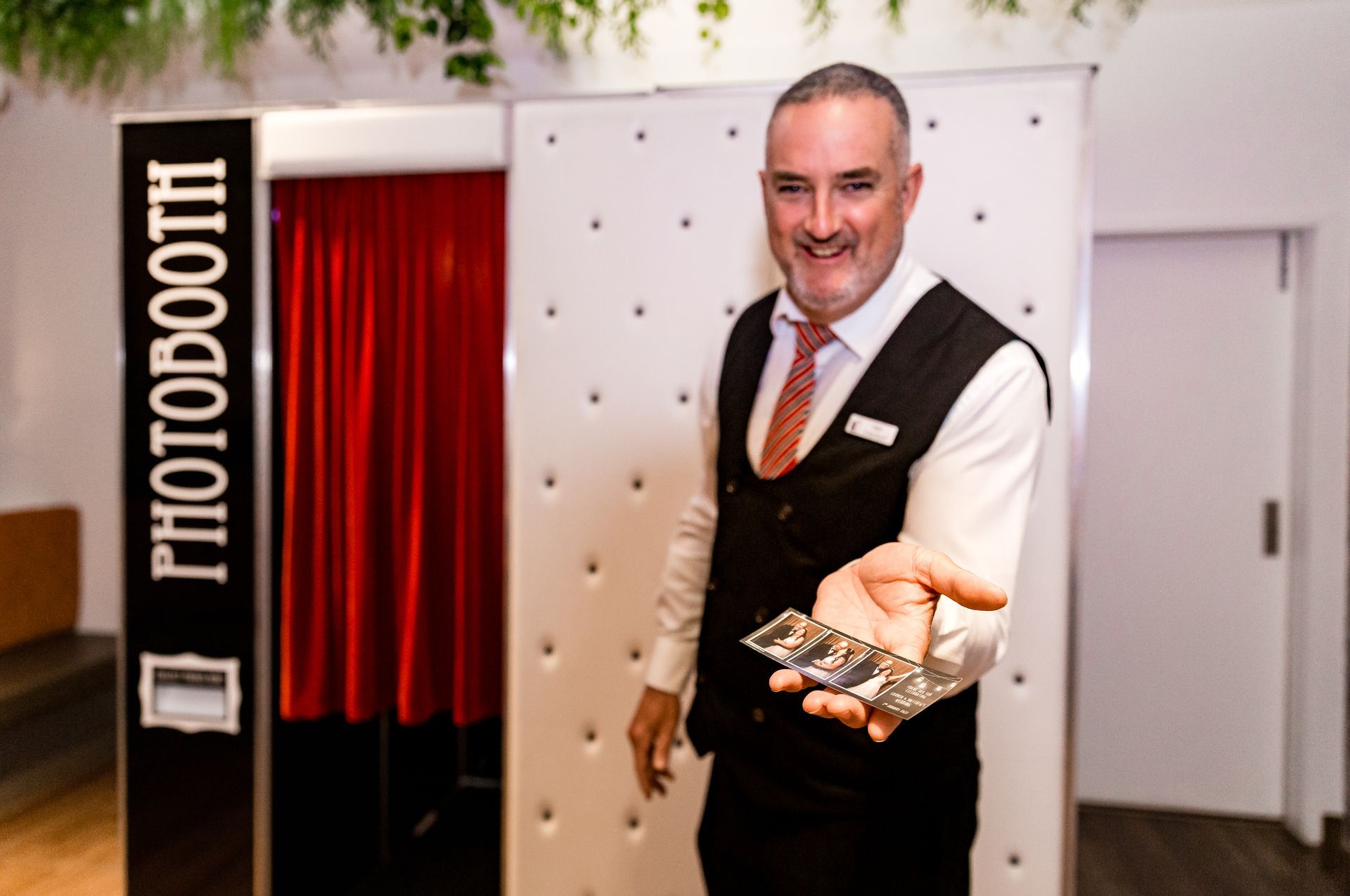 A man is standing in front of a photo booth holding a pair of keys.