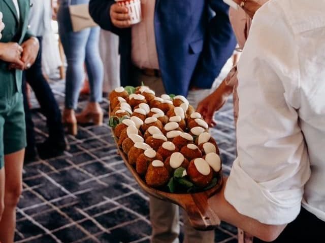 A woman is holding a tray of food in front of a group of people.