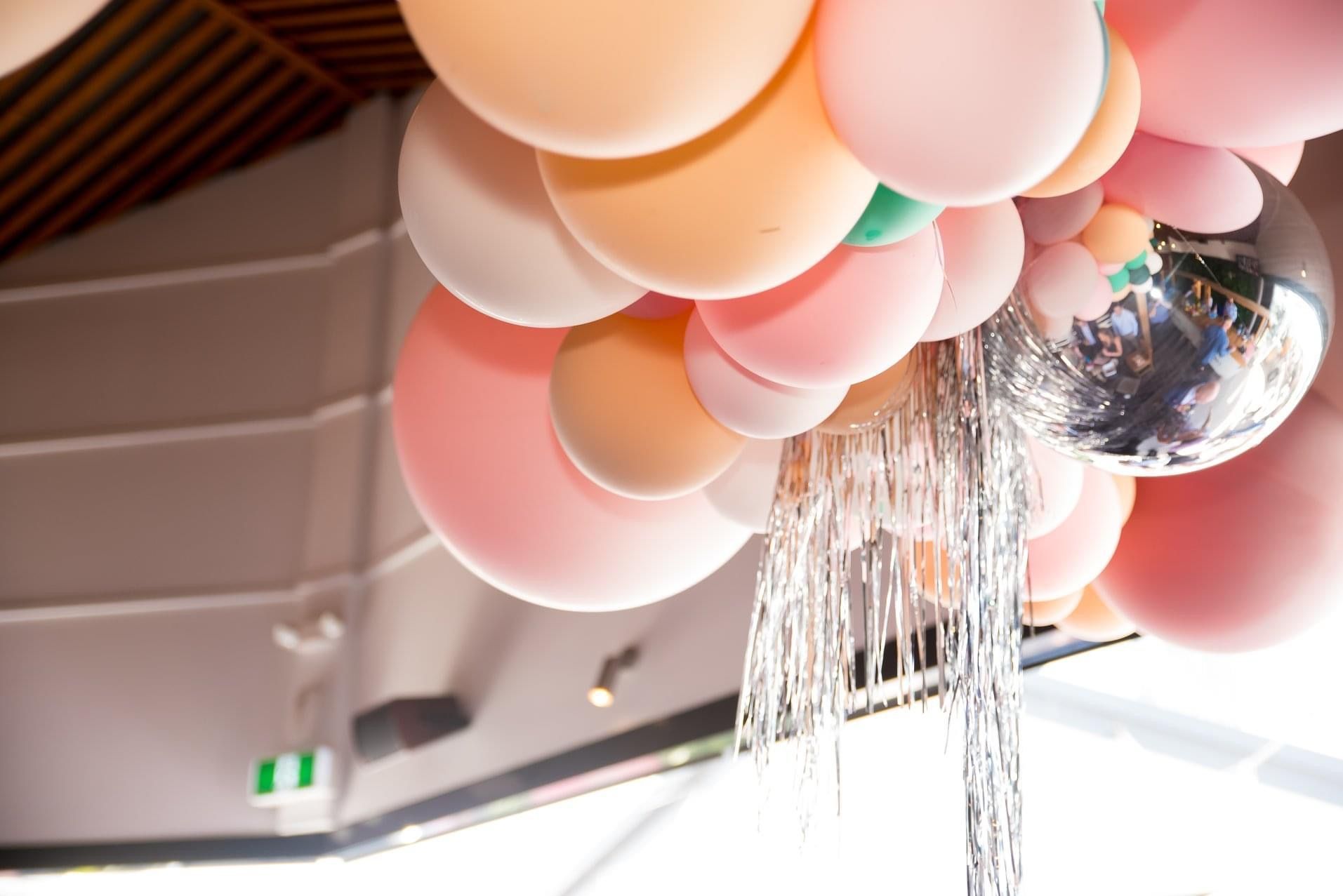 A bunch of balloons are hanging from the ceiling in a room.