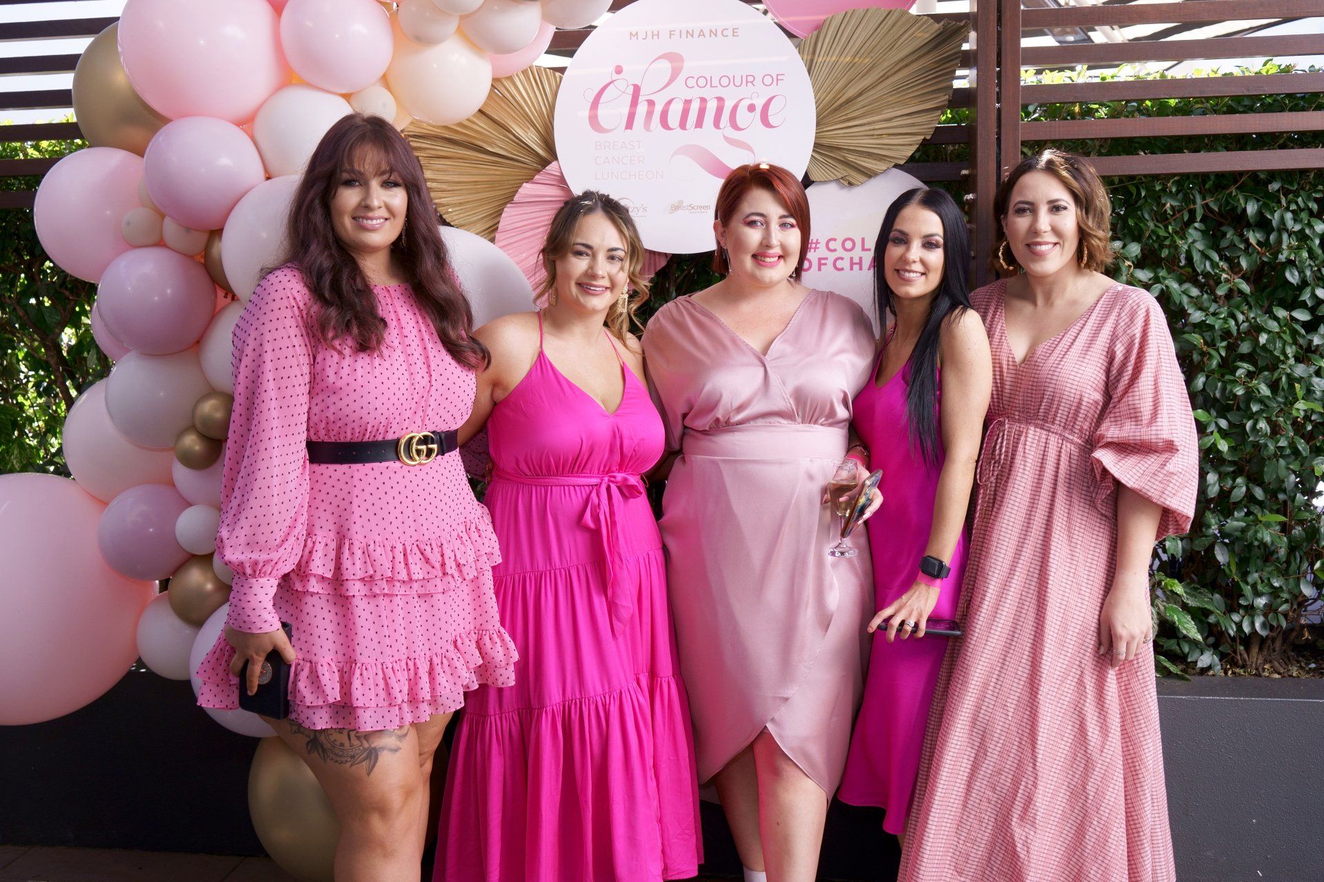 A group of women in pink dresses are posing for a picture.