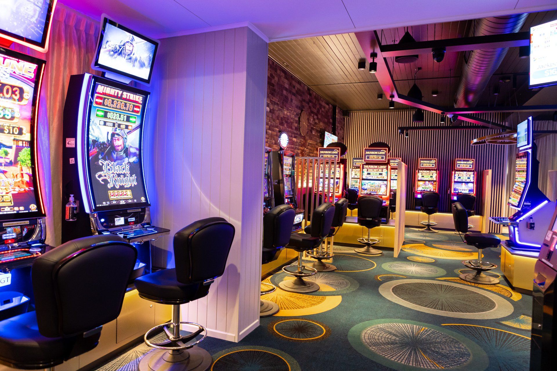 A casino with a lot of slot machines and chairs.