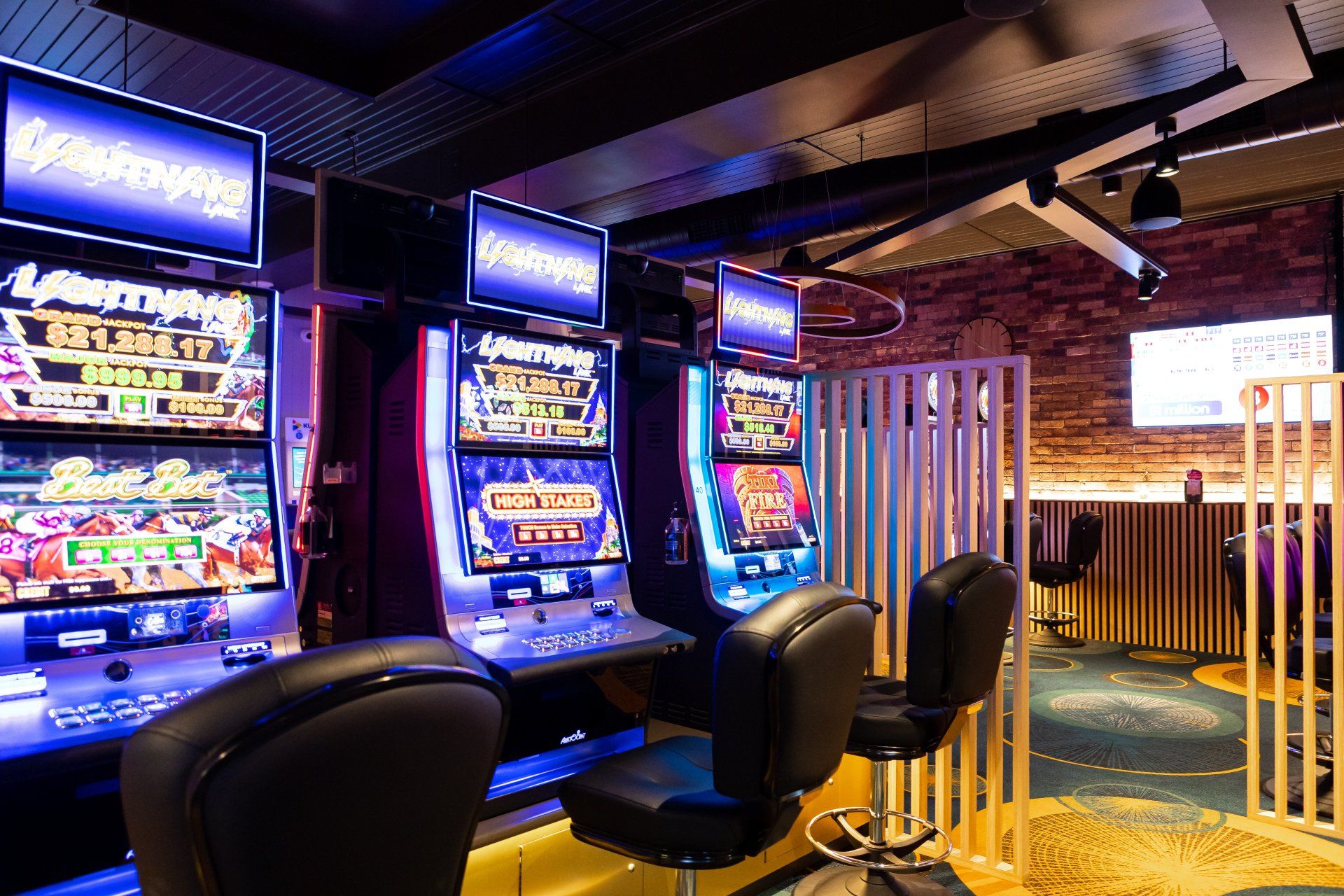 A row of slot machines in a casino with chairs.