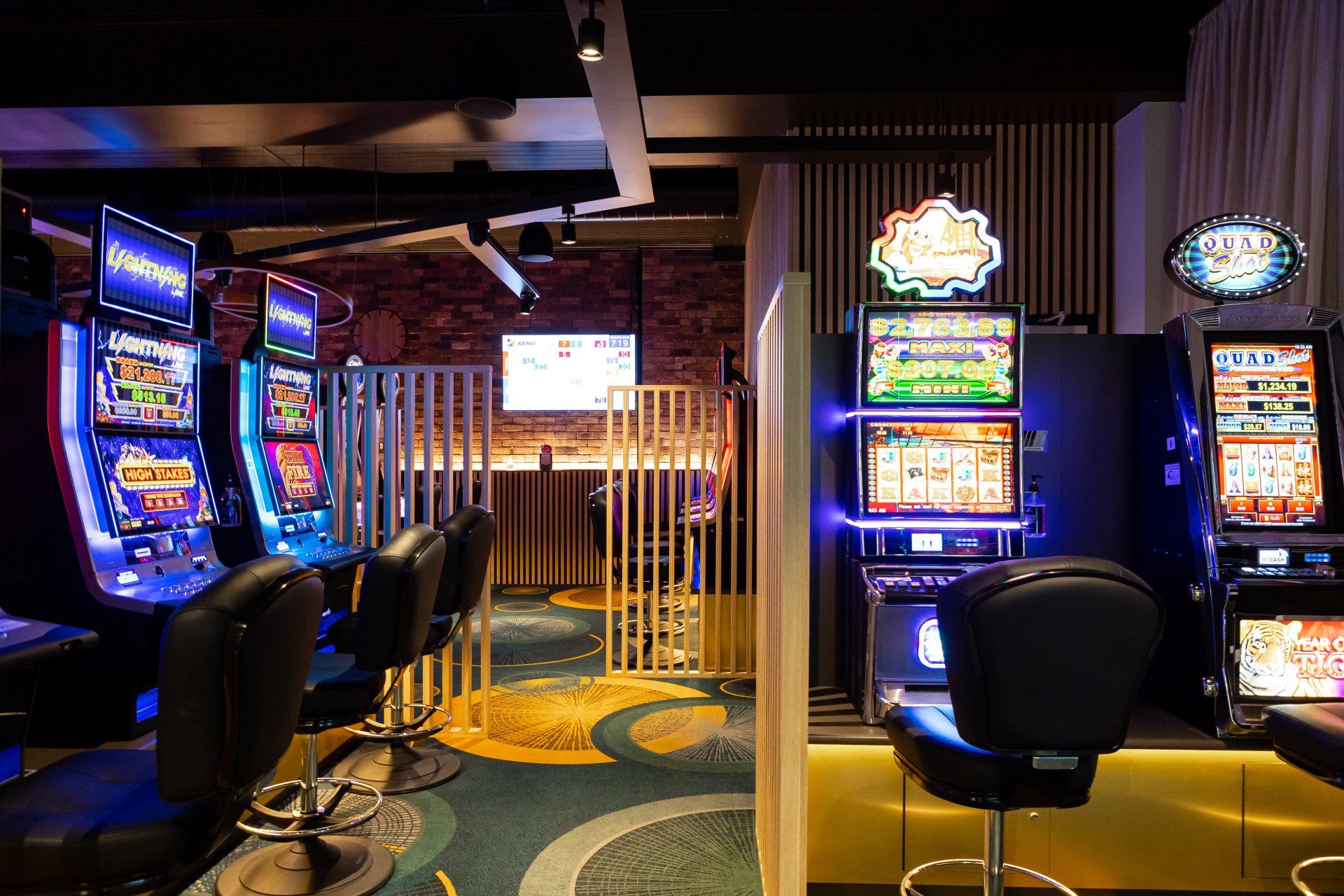 A casino with a lot of slot machines and chairs.