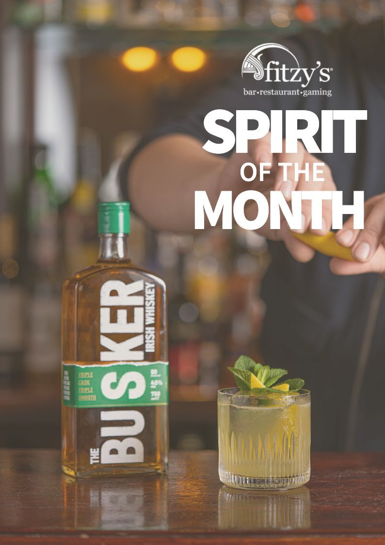 A bottle of busher irish whiskey next to a drink on a bar.