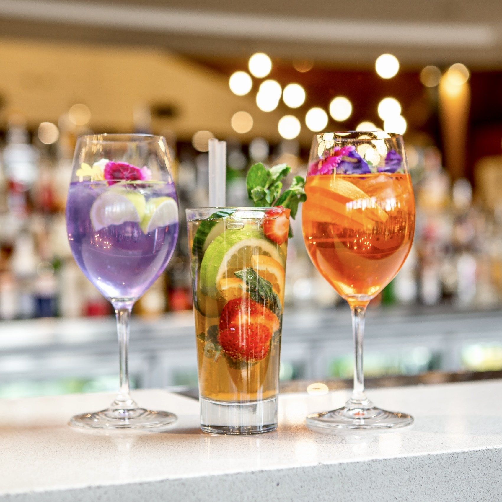 Three different drinks are sitting on a bar counter.