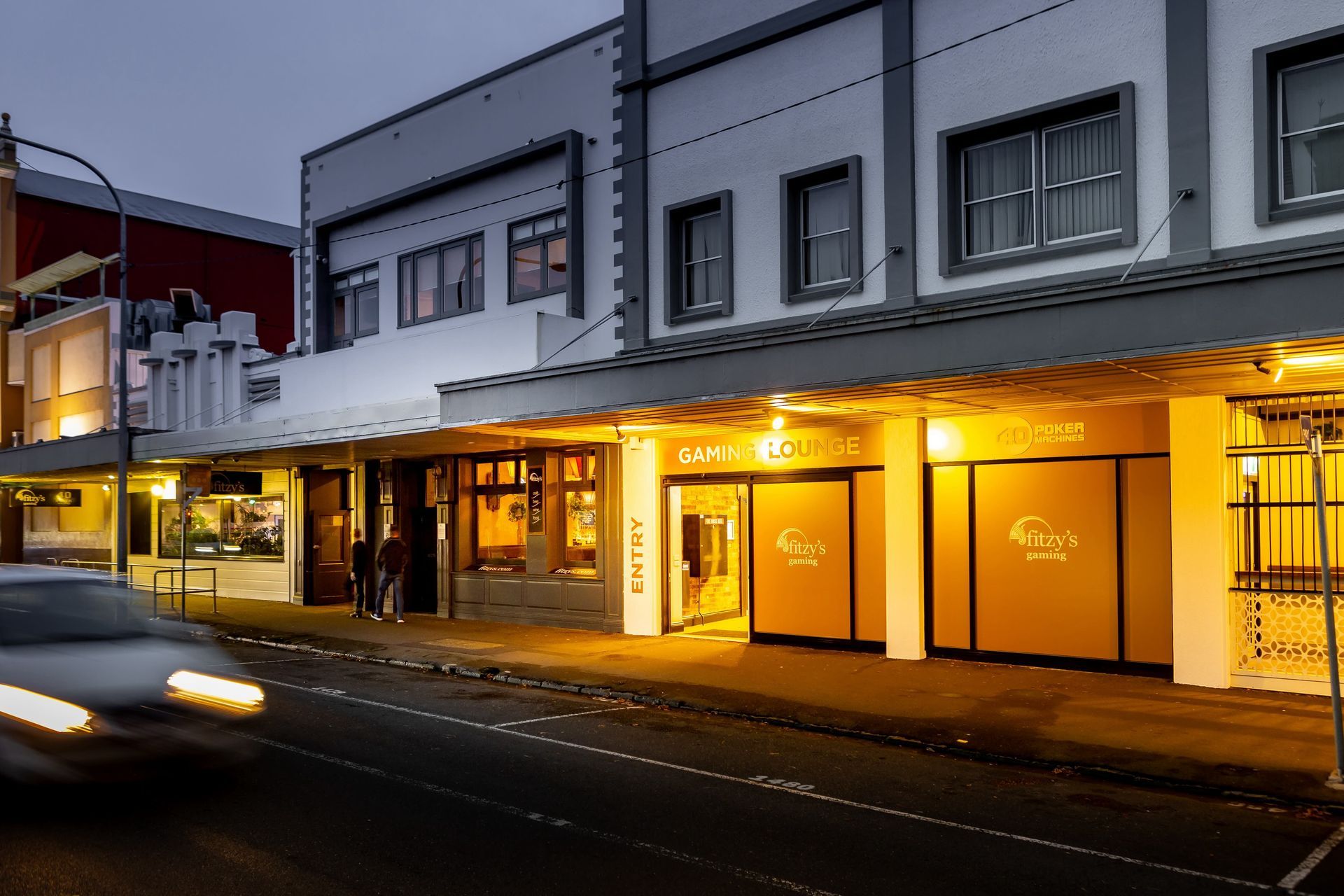 Street view of buildings at dusk, one labeled 