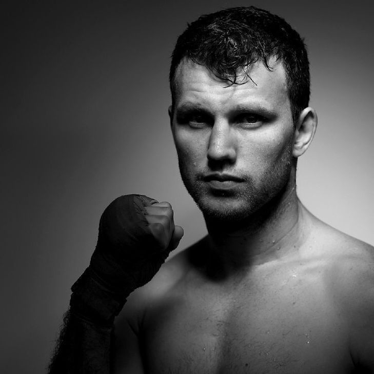 A black and white photo of a shirtless boxer with his fist in the air