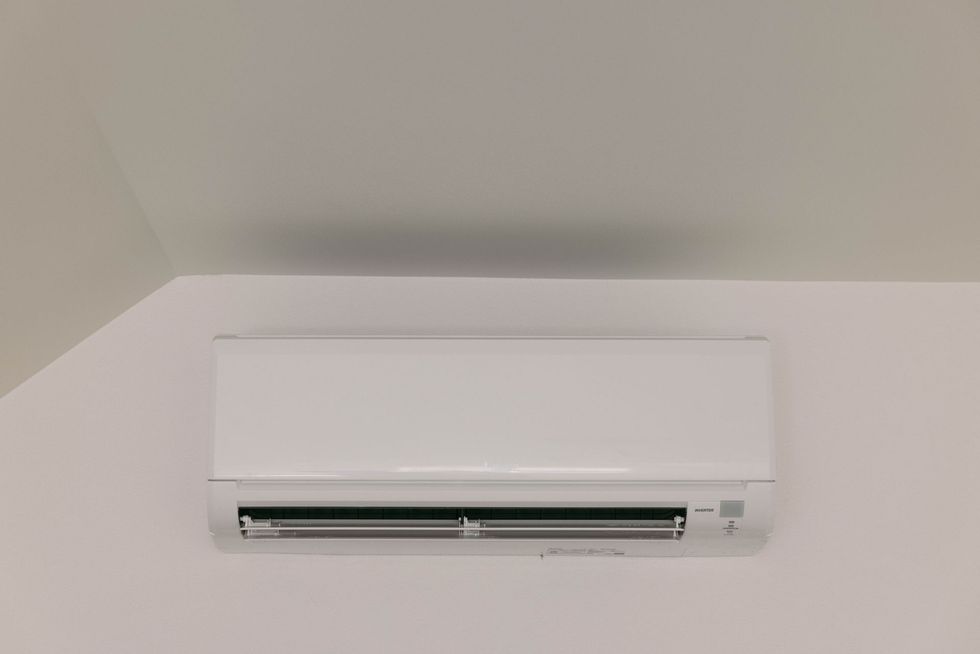 Air conditioning units with toolbox and gloves in backyard.