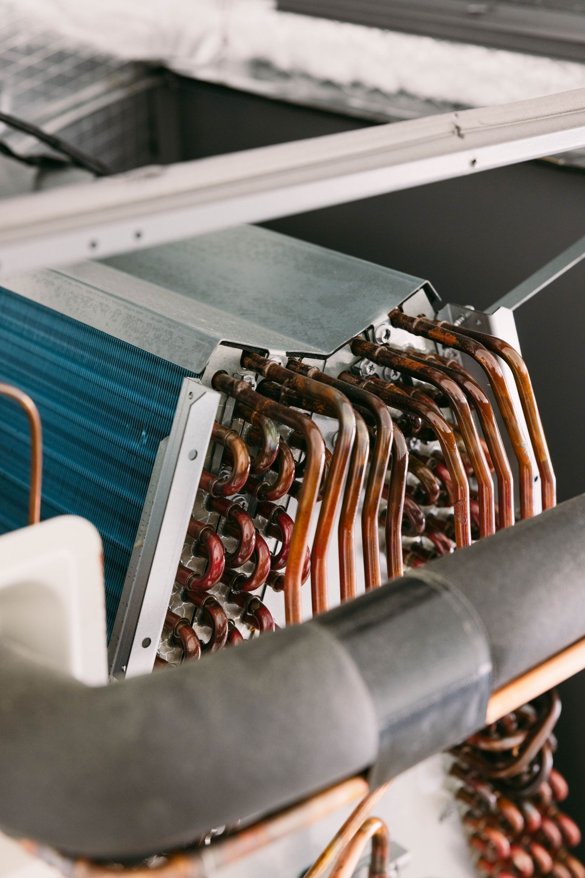 Close-up of copper coils and metal tubing inside an HVAC or refrigeration unit.