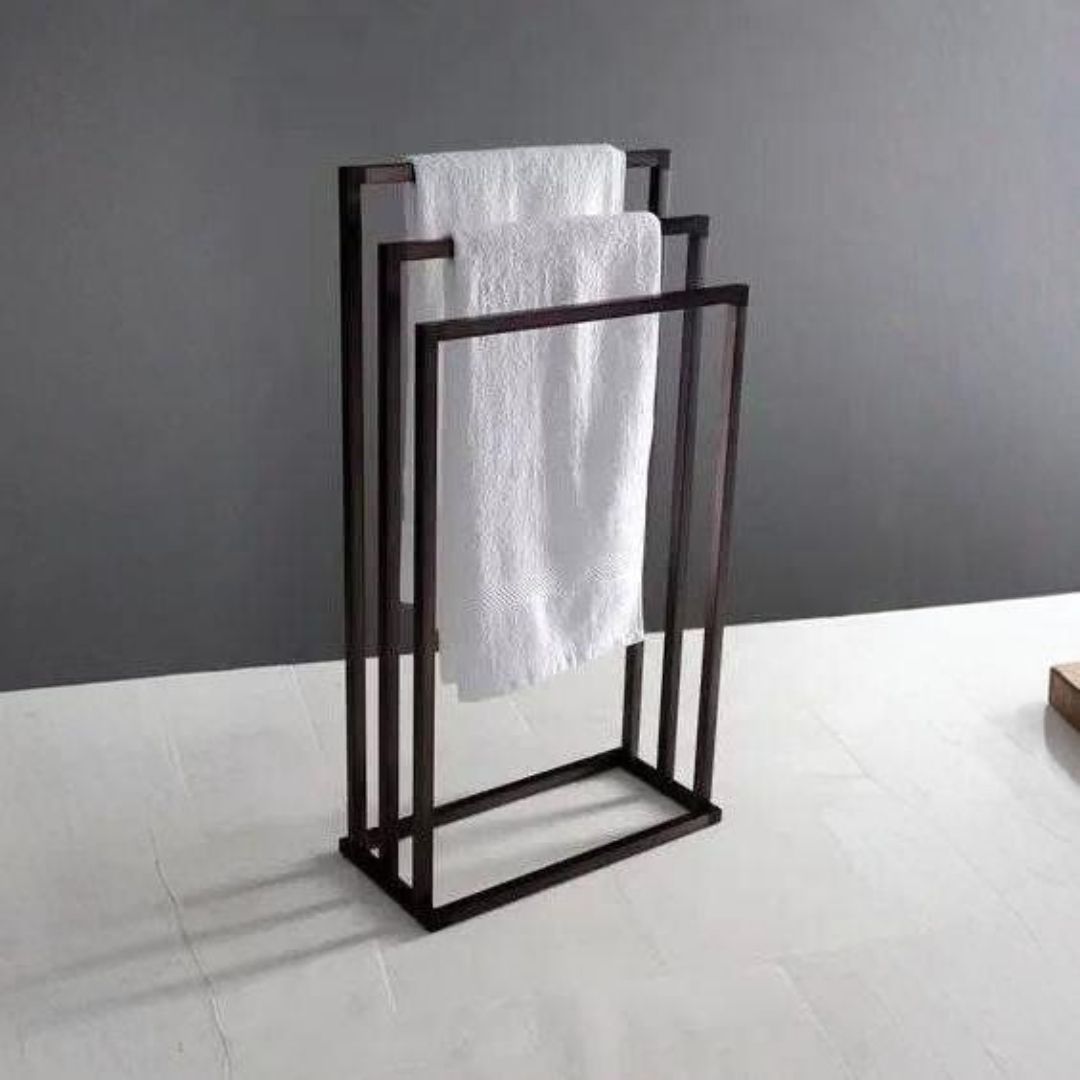 Toallero de metal oscuro con tres toallas blancas en un baño.
