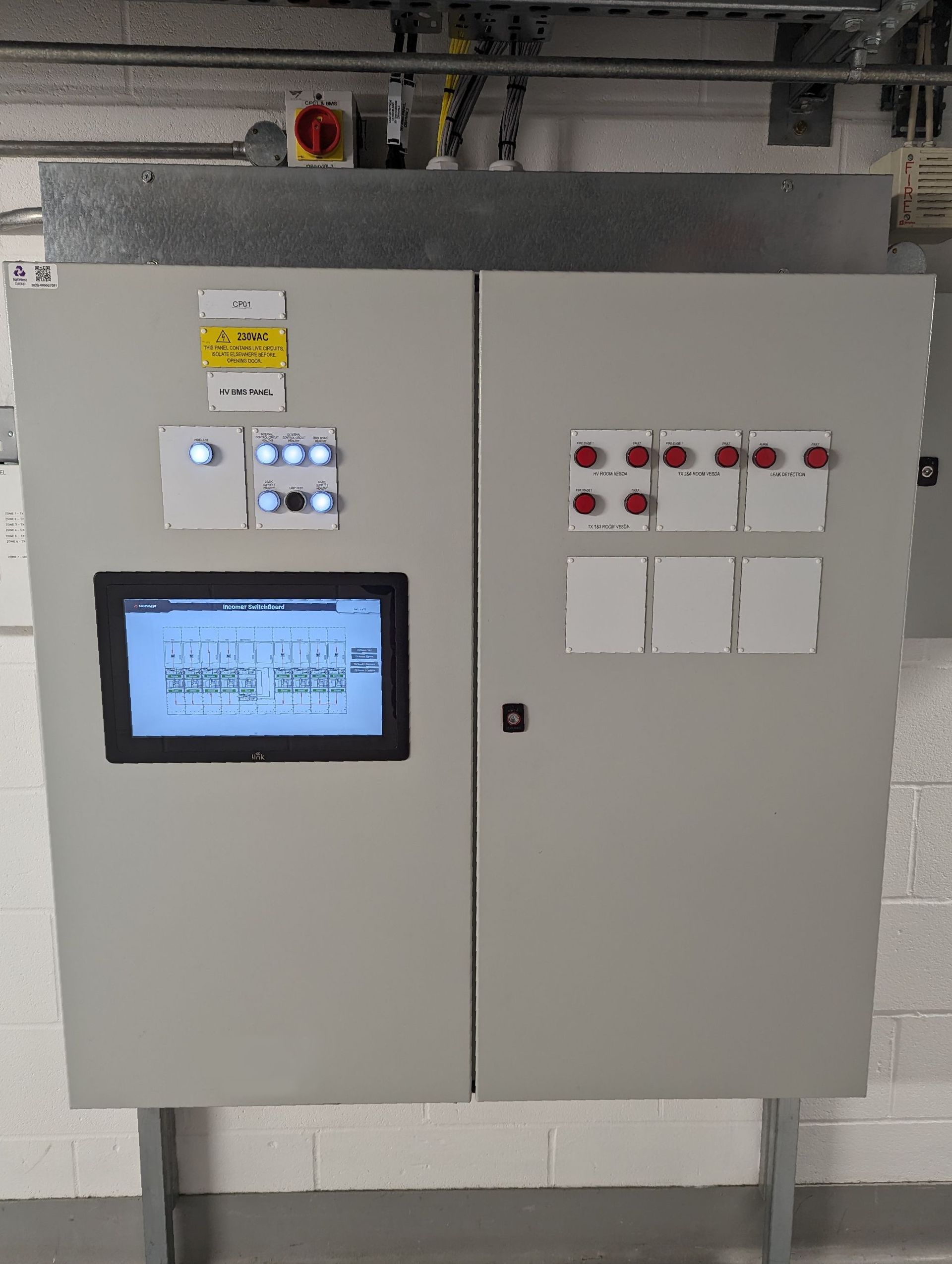 A control panel with a monitor on it is hanging on a wall.