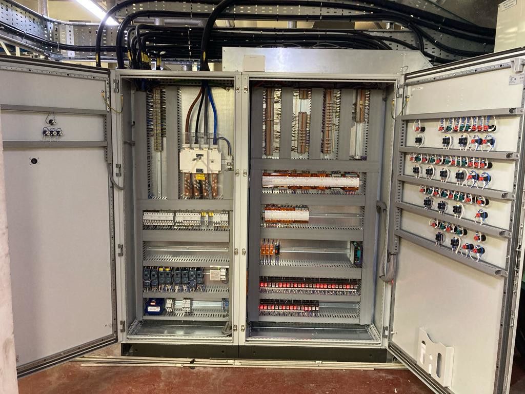 A large electrical cabinet with the doors open and lots of wires coming out of it.