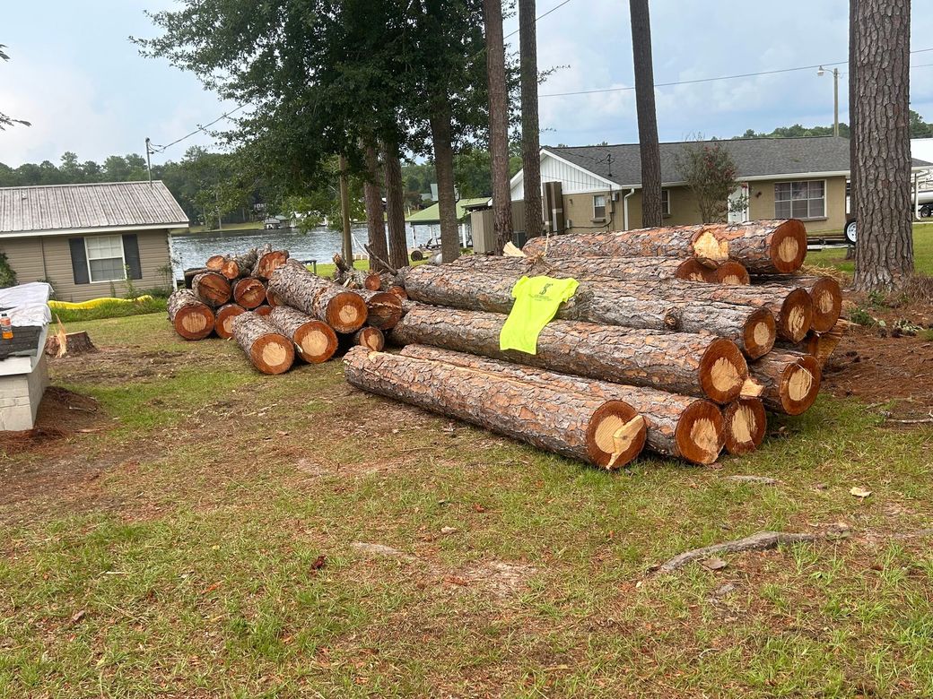 Stacked cut logs in a yard, with a neon yellow marker on top and houses in the background.