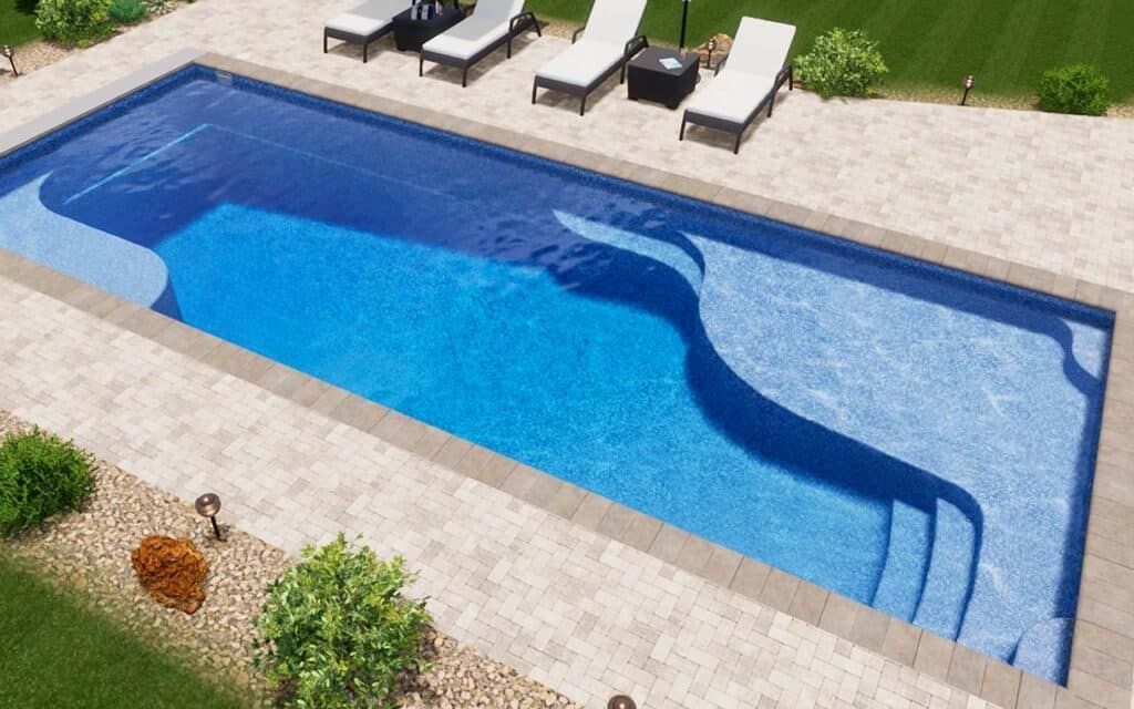 Rectangular blue swimming pool with lounge chairs on a paved patio