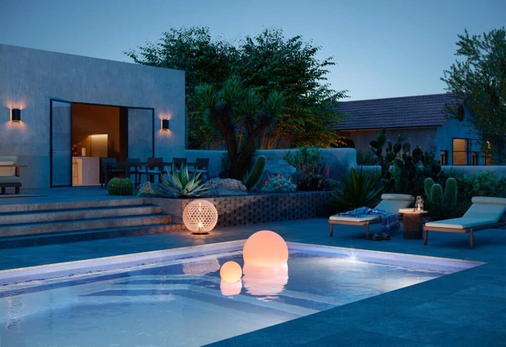 Modern backyard pool at dusk with glowing lanterns, lounge chairs, and a contemporary house backdrop