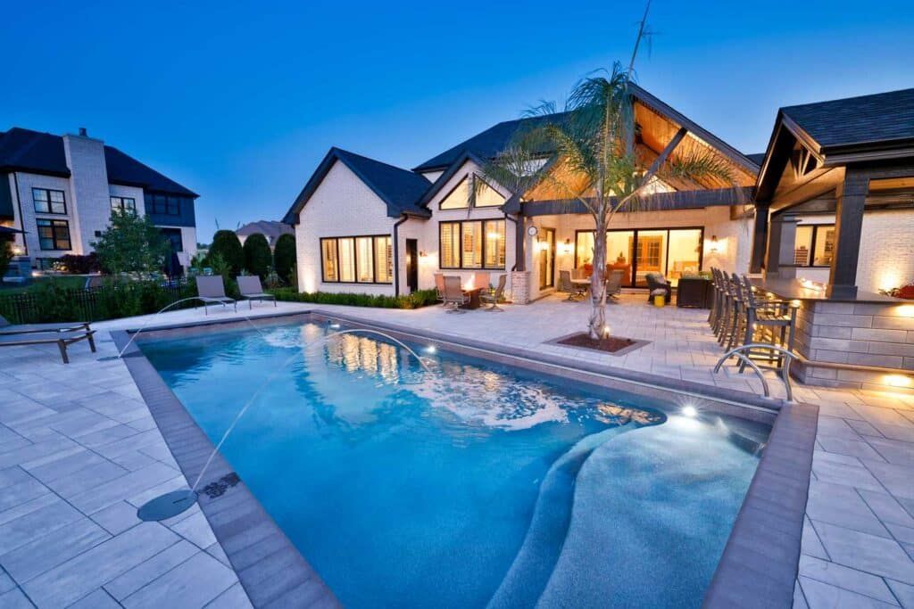Modern house with lit poolside patio at dusk