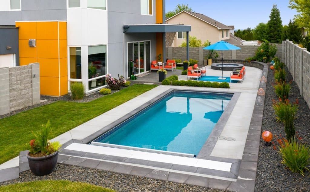 Modern backyard with a rectangular swimming pool, patio seating, and a landscaped garden