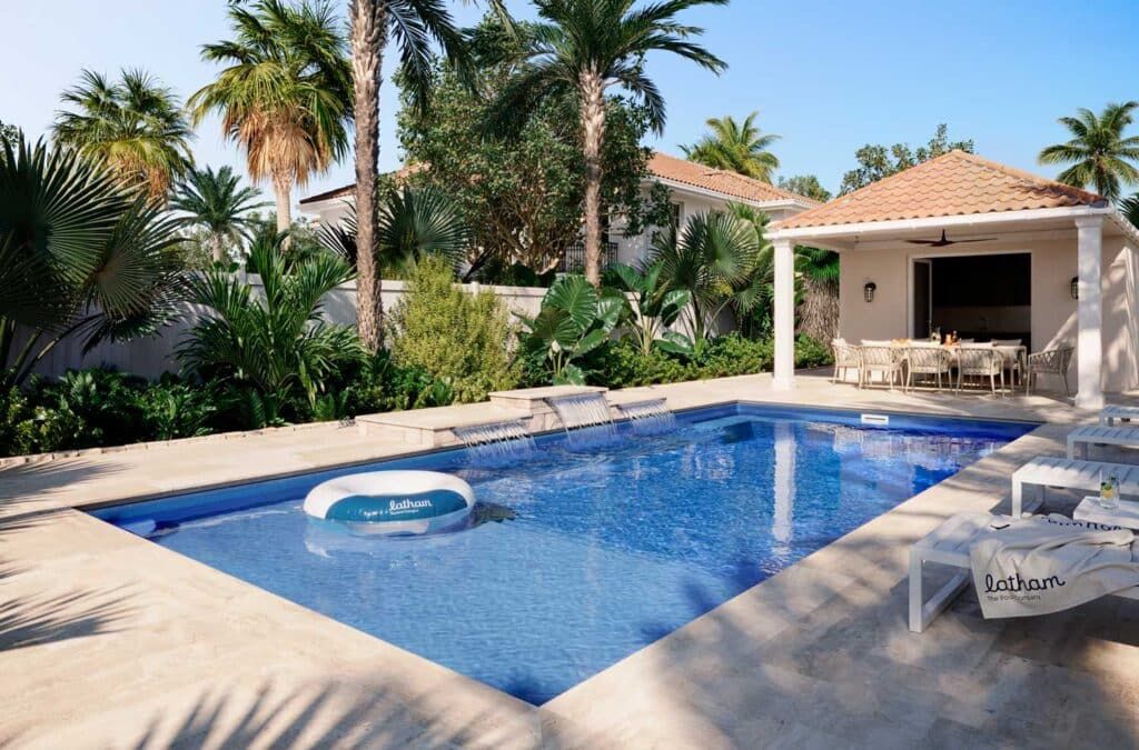 Backyard pool with lounge chairs, palm trees, and a shaded patio beside a white villa