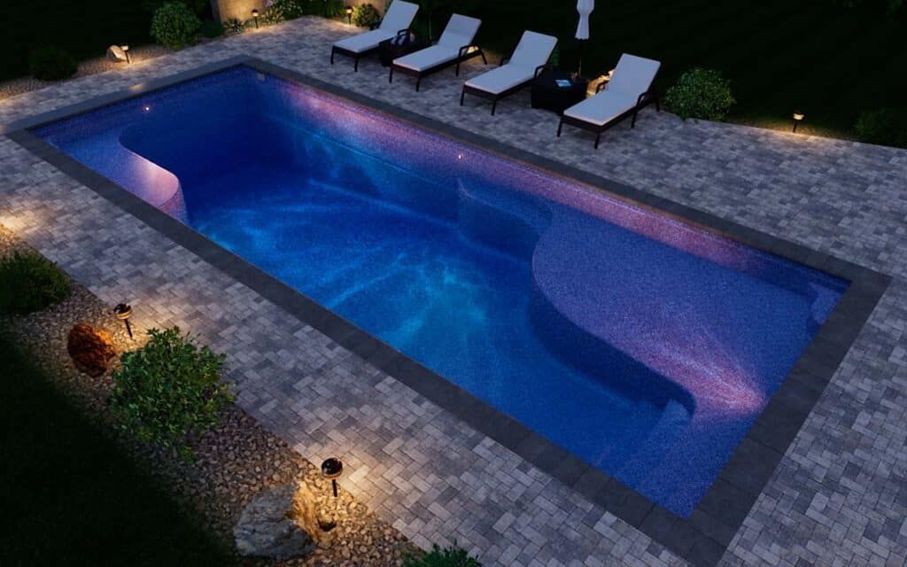 Modern backyard pool at night with blue water, stone decking, lounge chairs, and garden lighting