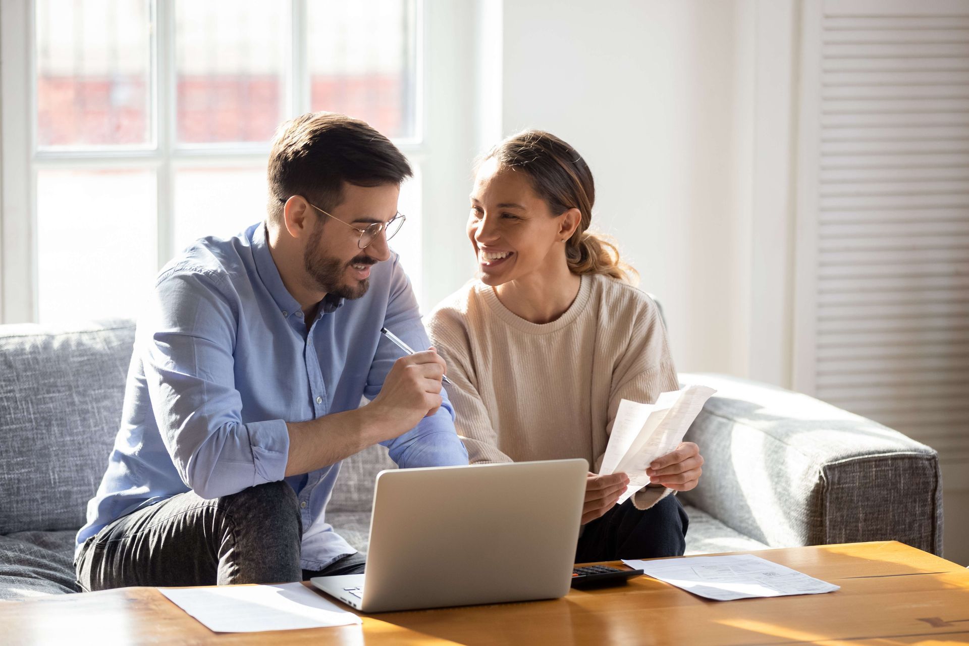 a man and a woman are sitting on a couch looking at a laptop
