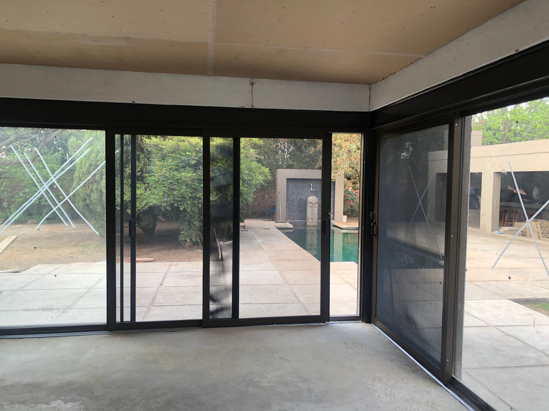 Sliding glass doors with security and wildlife screens opening onto a backyard patio with a swimming pool.