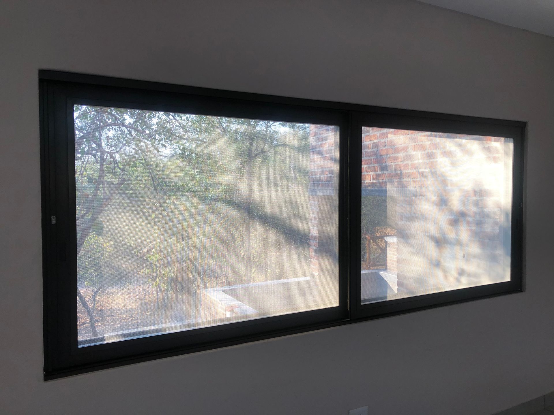 A rectangular window with a dark frame with screen solution installed by SunShade.