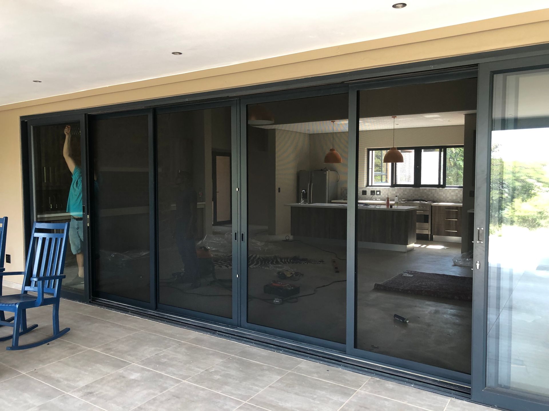 Large sliding glass doors with dark security mesh screens installed on a patio by SunShade.