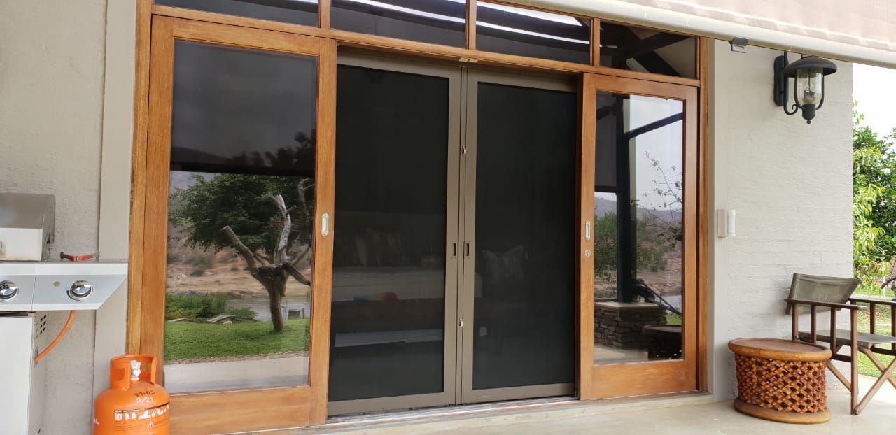 A wooden-framed sliding door with black security mesh screens on a patio installed by SunShade.
