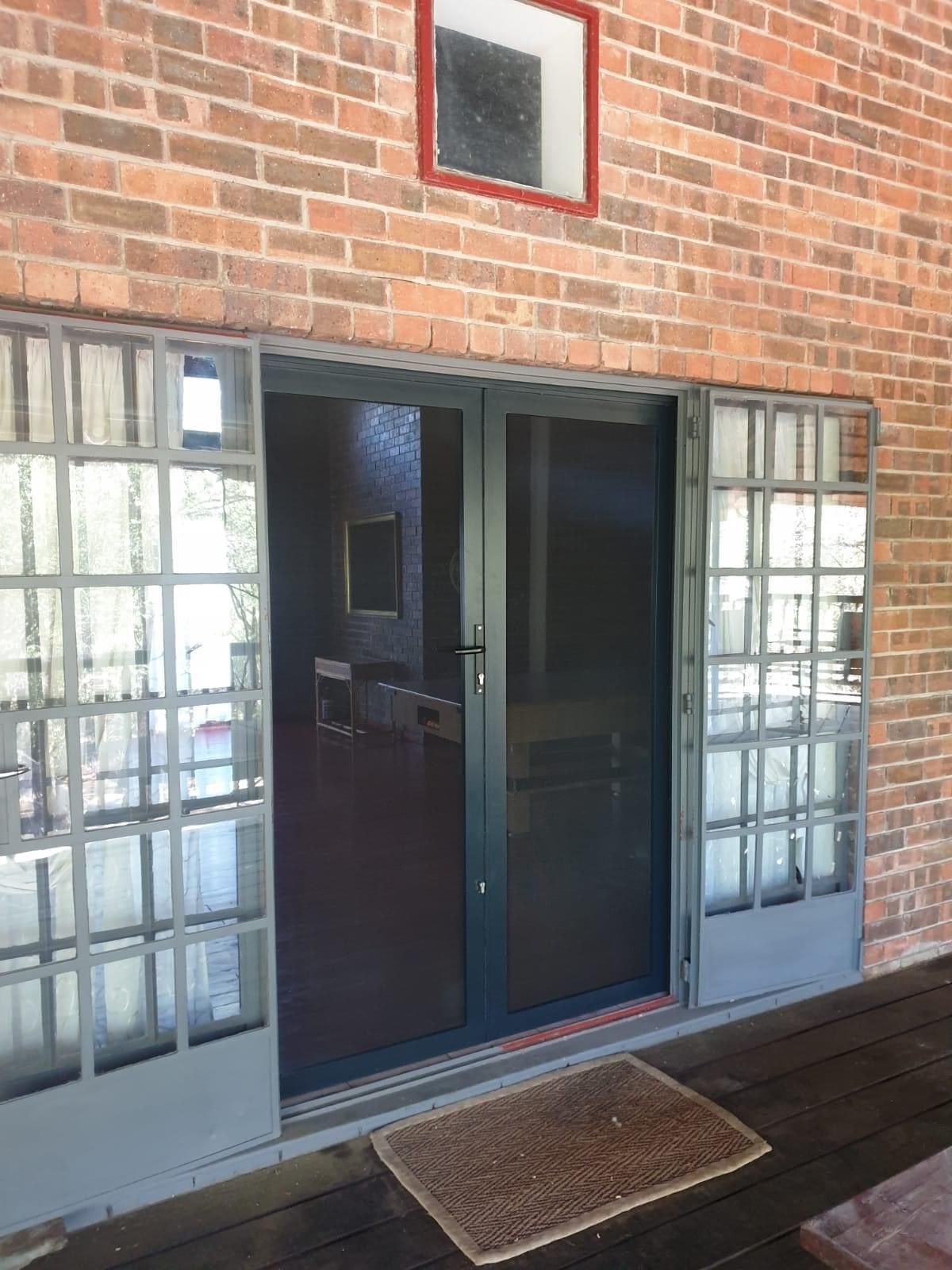 A dark-framed double door with glass side panels, with screen solutions installed by SunShade.