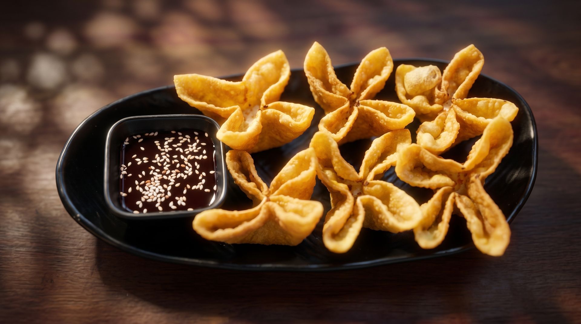 Black serving dish with sesame dipping sauce and golden star-shaped fried snacks on a wooden table