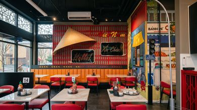 Colorful restaurant interior with red booths, patterned walls, and a glowing sign above the dining area.