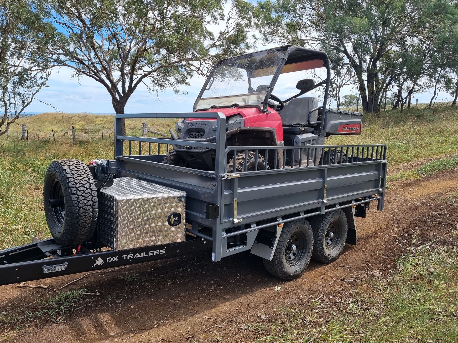 A 3-way tipper trailer on dirt road carrying a 4x4 to farm. 
