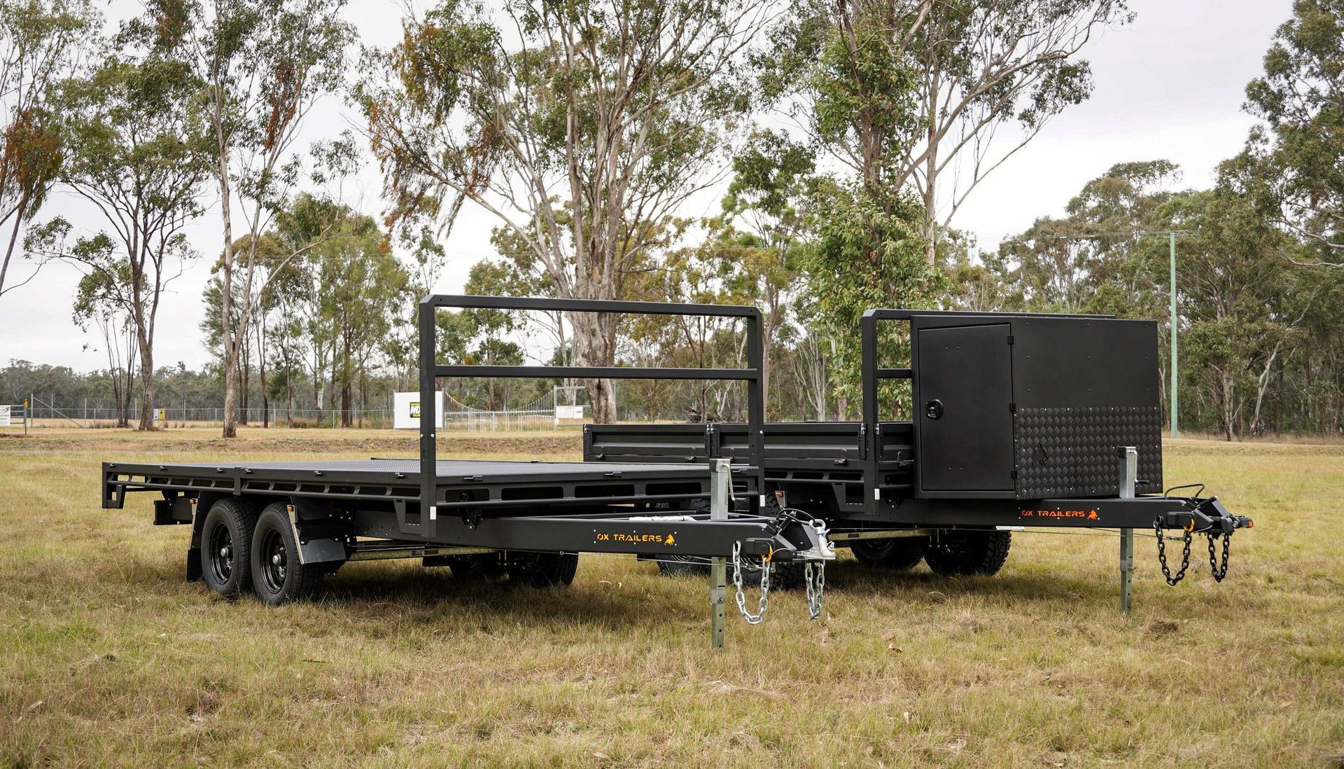 three flat top trailers by a country dam.