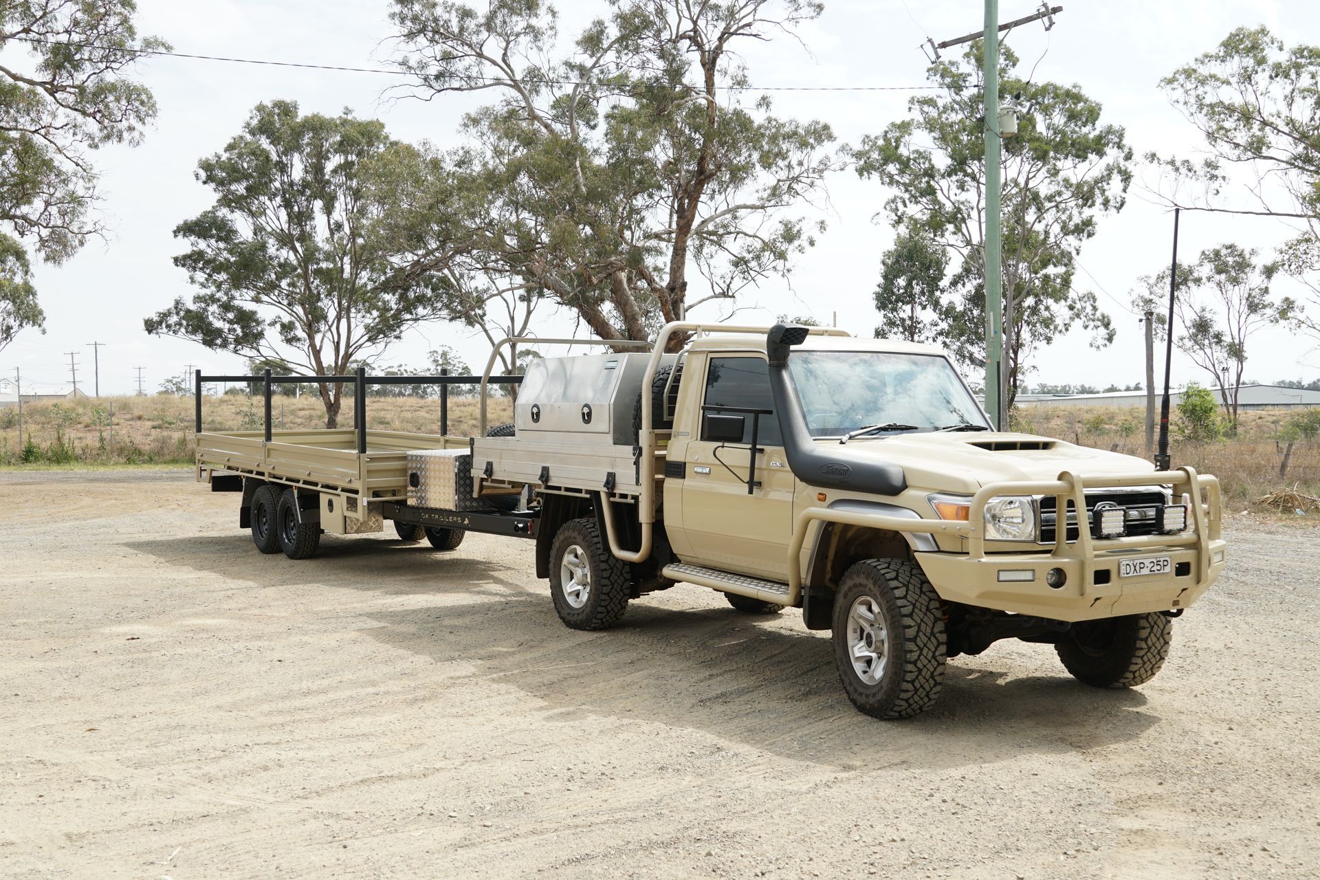 Sandy Taupe Flat Top Trailer getting towed behind sandy taupe Land Cruiser. Painted custom to match clients expectations.