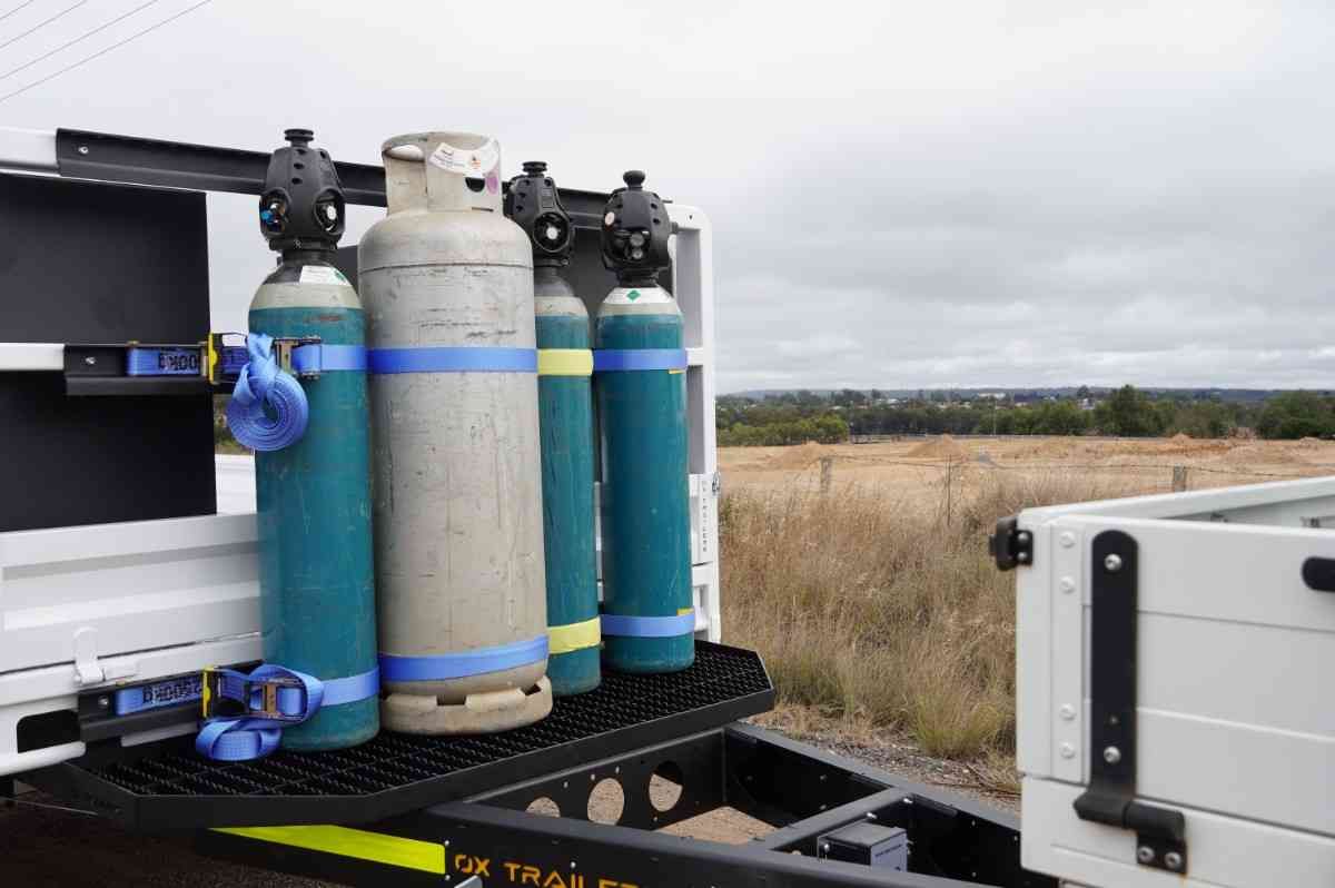 Drawbar-mounted gas bottle frame on an ox trailer.