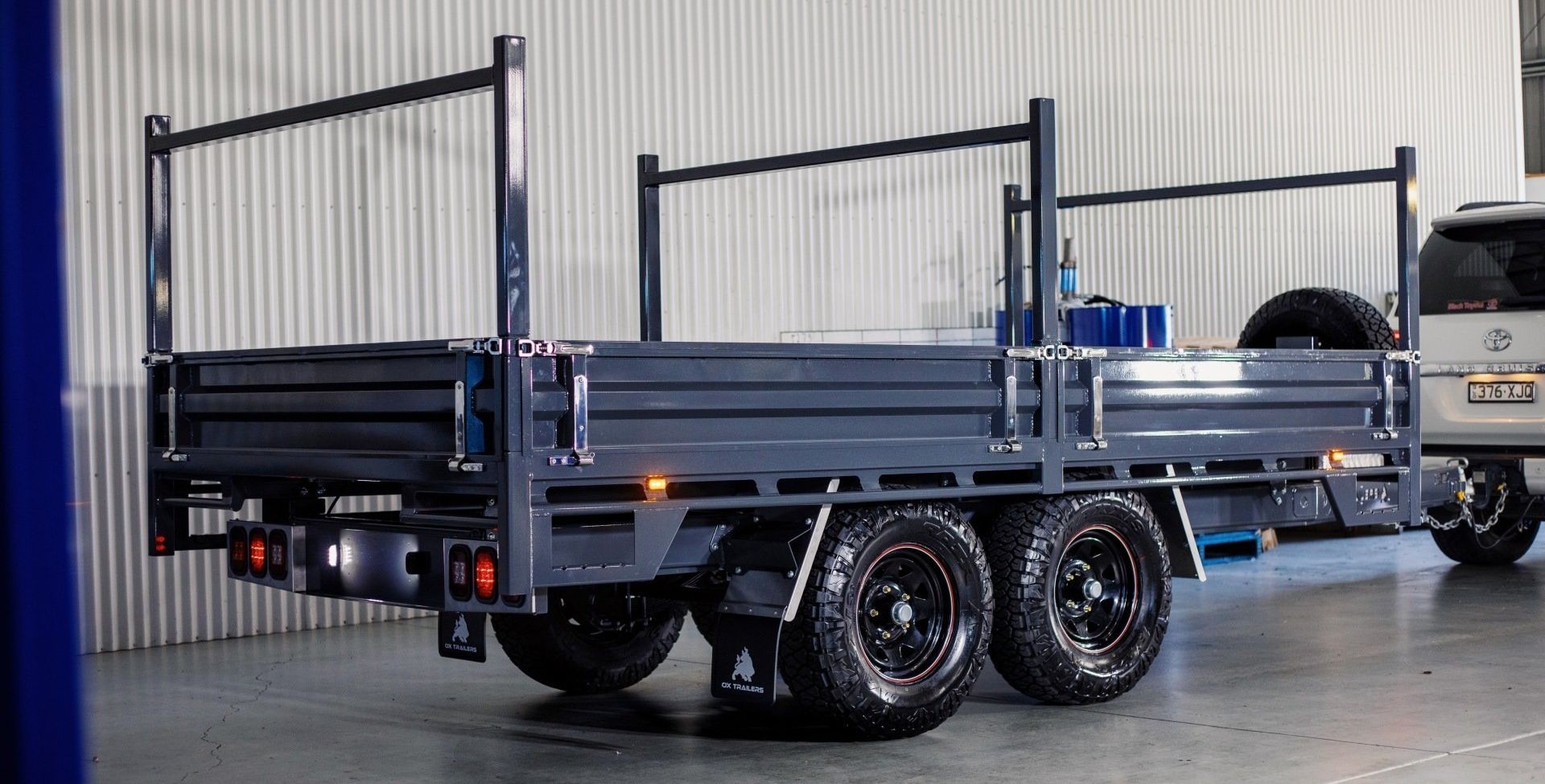 A clean 4.5T Flat Top Trailer with ladder racks, headboard, and tandem tyres under factory lights on polished concrete.