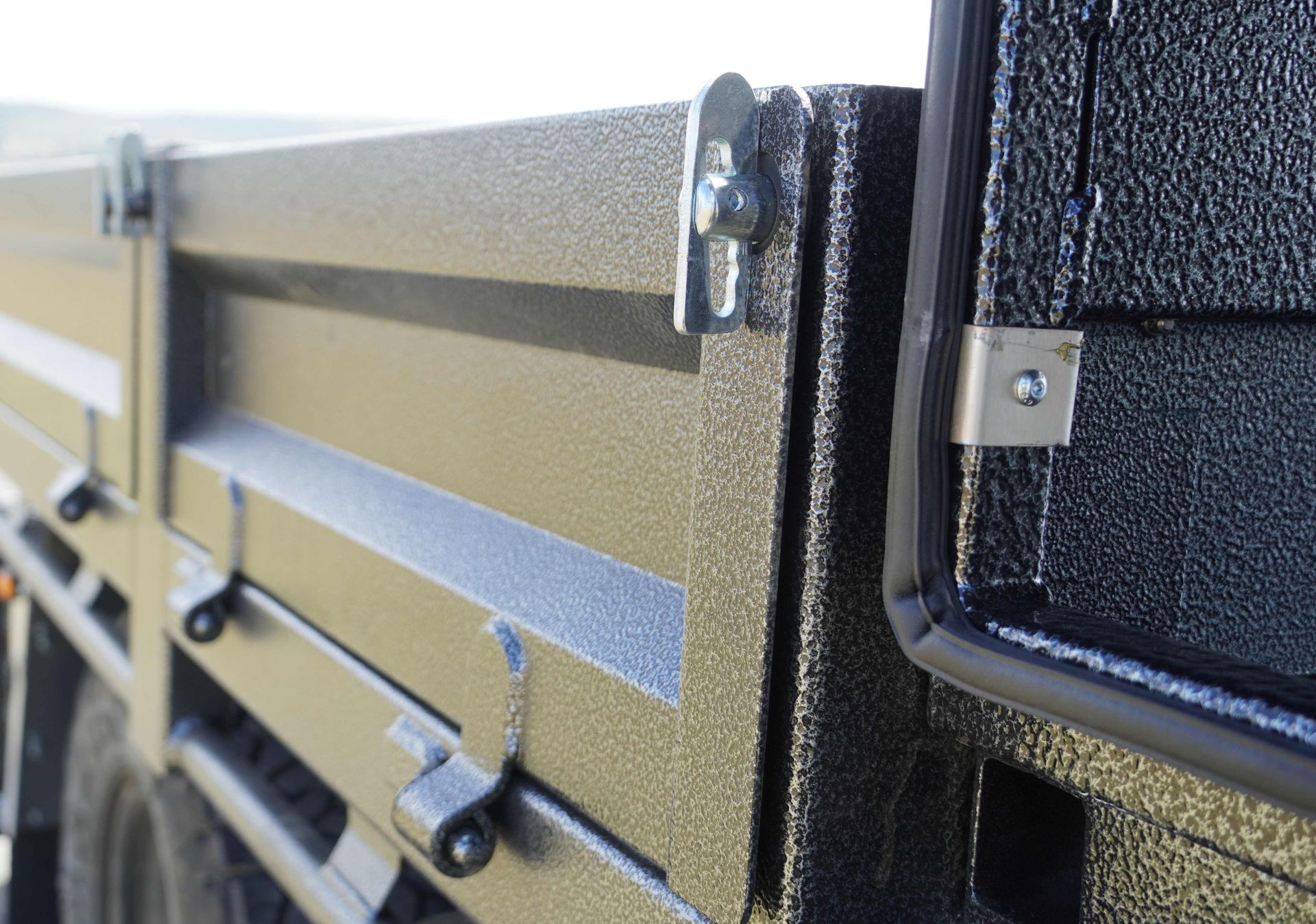 The bolted hinges and anti-buce latches of an ox trailer trade series flat top trailer.