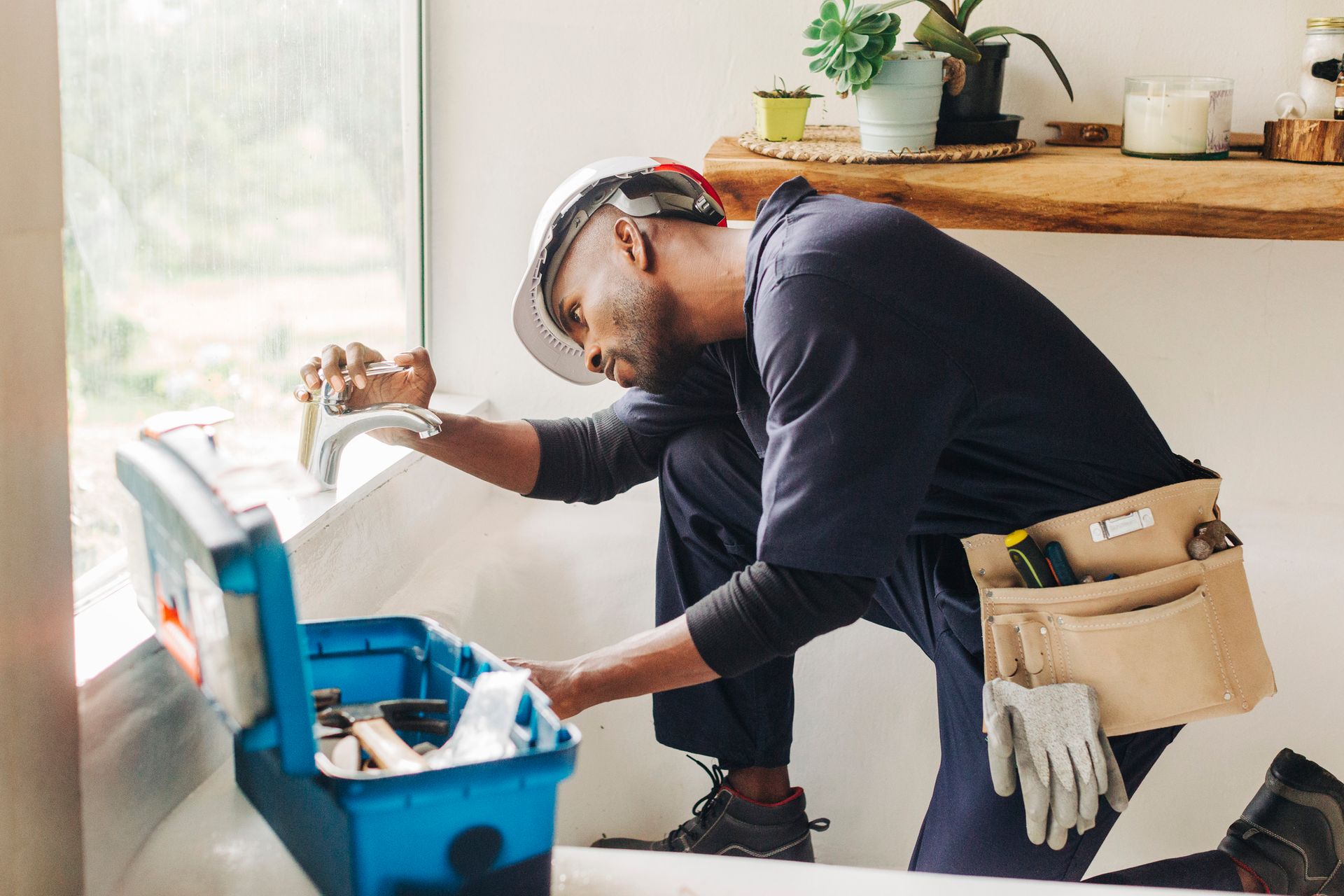 A male plumber trying to fix a bathroom faucet.