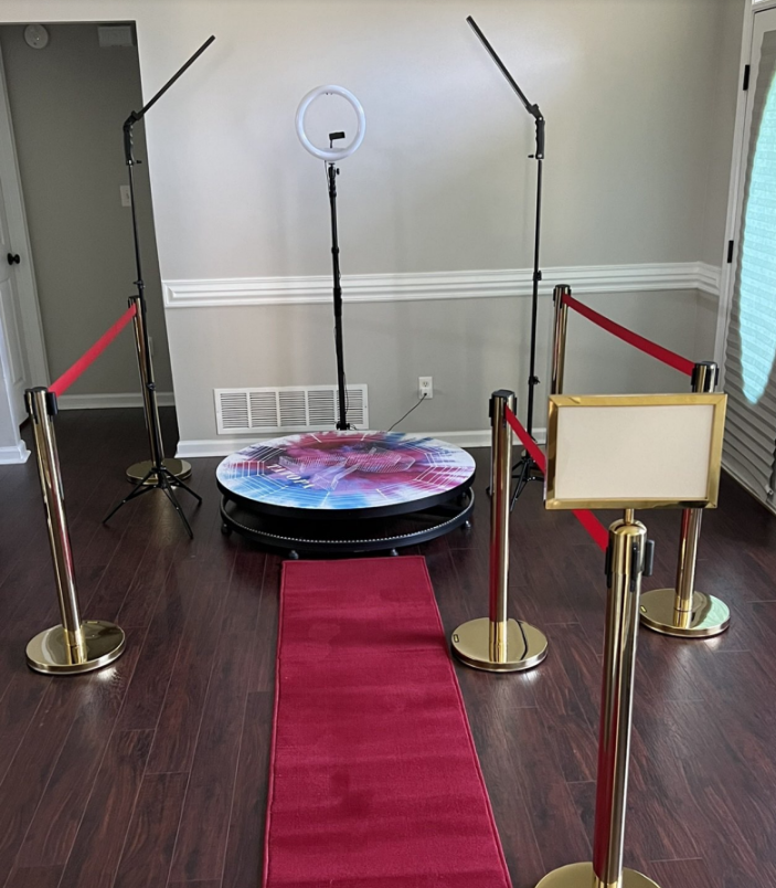 Red-carpet photo booth with ring light and stanchions in a lobby, no people present