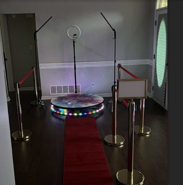 Red carpet aisle leading to a lit circular stage with mic stand and ring light in a room
