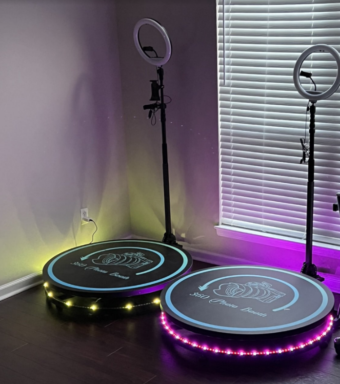 Two lit ring lights on stands beside round LED platforms in a room with blinds.