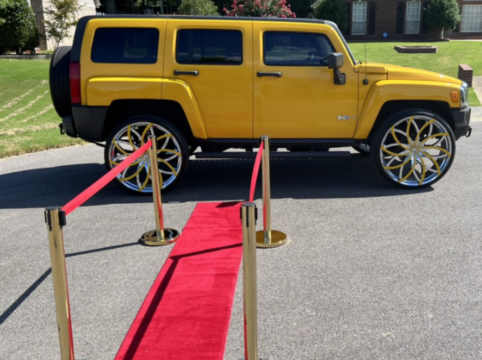 Yellow SUV on display behind a red carpet and stanchions outside a building