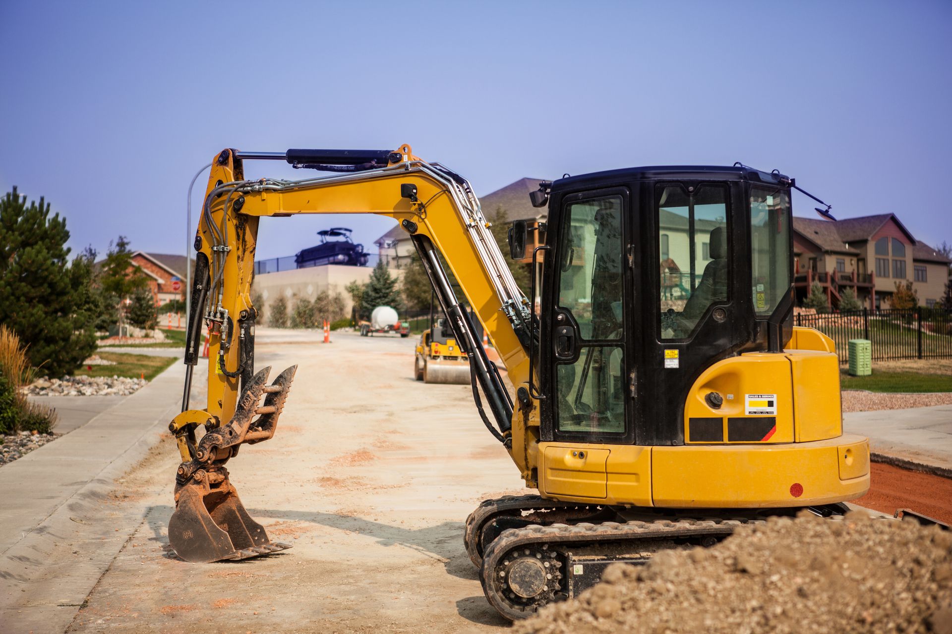 A yellow excavator is sitting on top of a pile of dirt on a construction site.