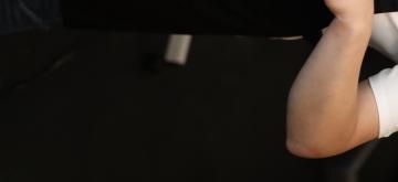 Close-up of a bent arm in a white sleeve against a dark background