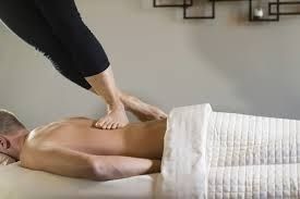 Massage therapist applying pressure to a client’s back on a treatment table