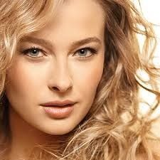 Close-up portrait of a woman with wavy blonde hair and a neutral expression