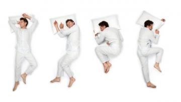 Four people in white pajamas jump playfully on white pillows against a white background.