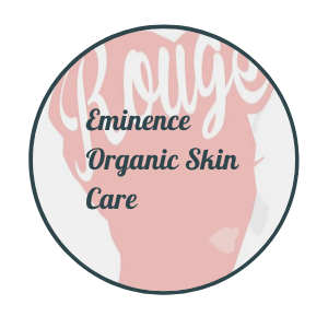 Pink circular logo reading “Eminence Organic Skin Care” with white script text and dark border