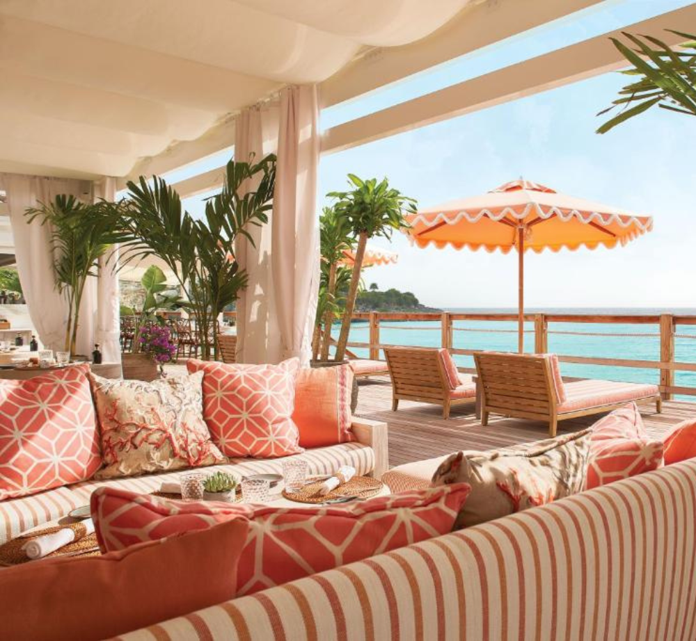 A living room with a couch and umbrella overlooking the ocean