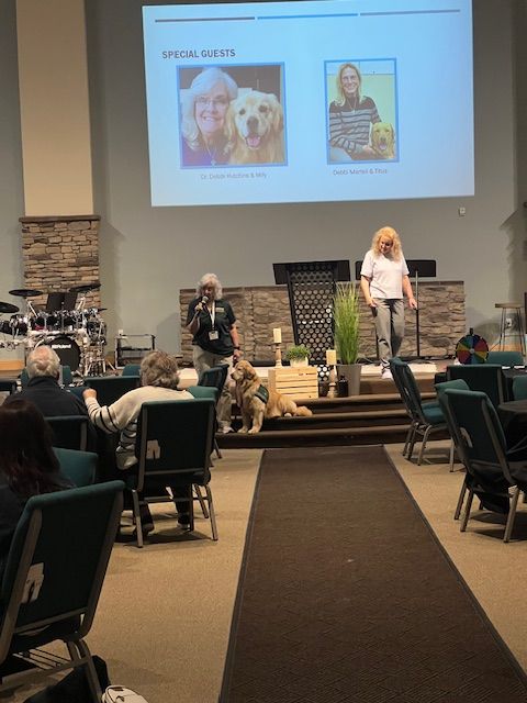 Conference room stage with two presenters and a slide showing pet photos behind them